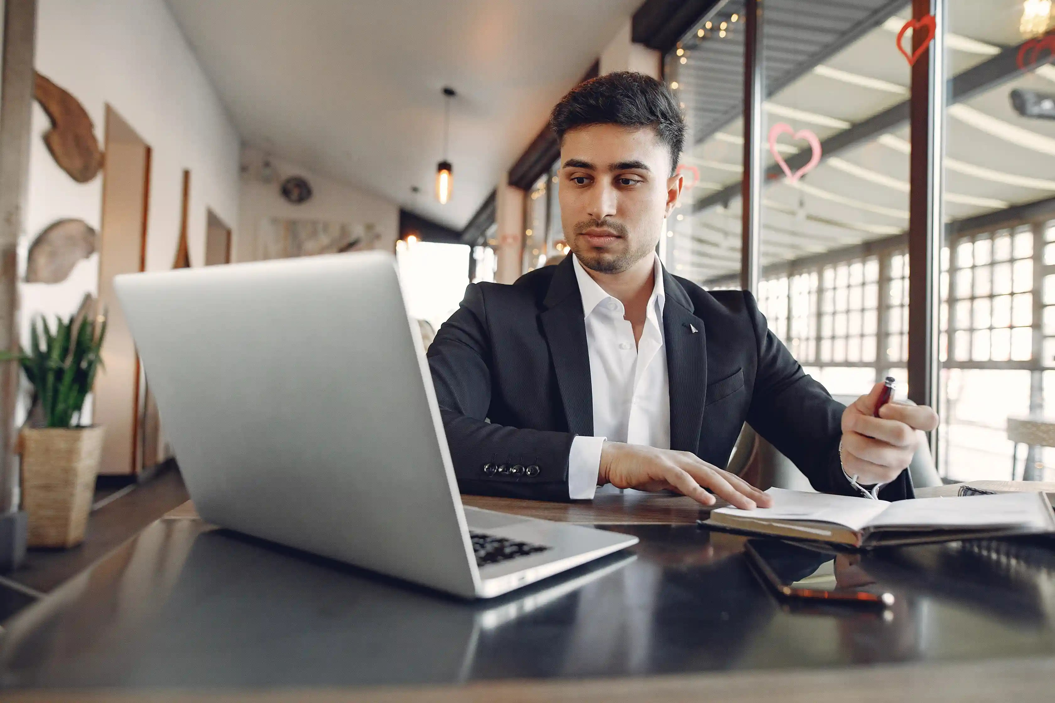 A focused professional reviewing documents and working on a laptop at a café table